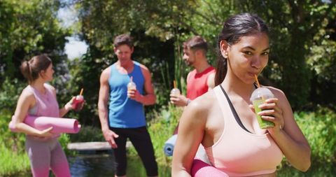 Group Doing Outdoor Yoga, Drinking Health Detox Juices