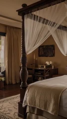 Vertical video panning over luxurious four-poster canopy bed with sheer curtains swaying