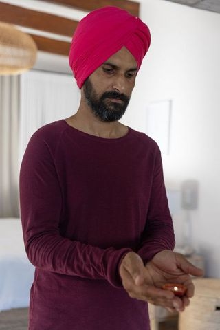 Man in turban holding lit oil lamp reflecting spirituality in bedroom