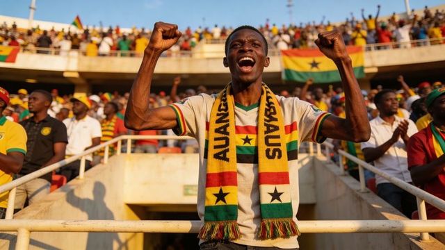 Ghanaian man cheering in stadium raising fists wearing ghana flag scarf and jersey