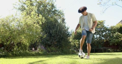 Man practicing soccer skills on sunny lawn