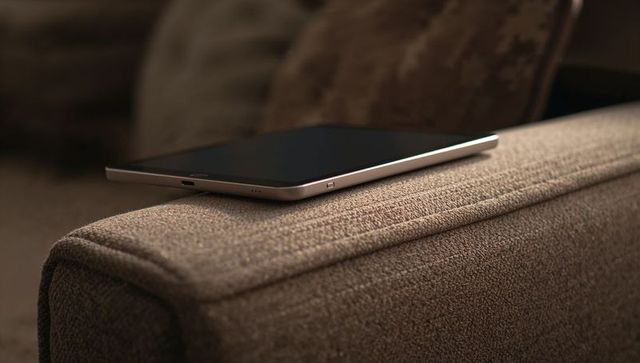 Slim smartphone resting on sofa armrest closeup showing metallic edge and charging port