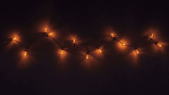Warm amber string lights casting soft halos on dark minimal backdrop for ambient mood