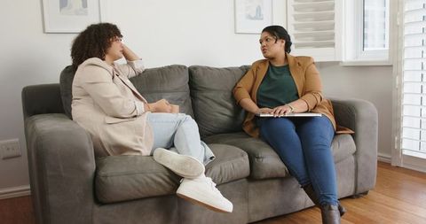 Home Therapy Session with Counselor Listening and Client Sharing on Sofa