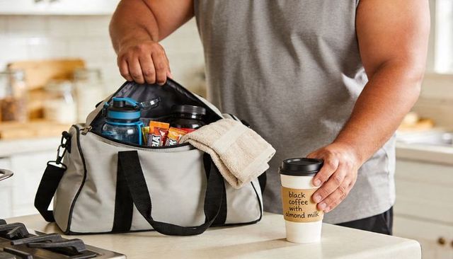 Gym bag essentials man packing water bottle protein bars towel coffee before workout