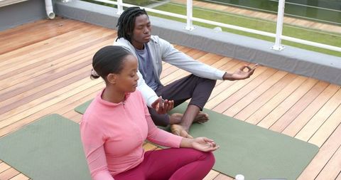 African American couple meditating on rooftop deck during peaceful outdoor yoga session