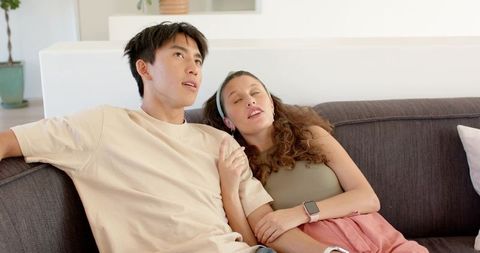 Young couple cuddling on couch relaxing with smartwatch and headband in minimal living room