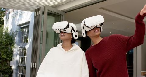 Friends engaged in virtual reality outdoors under pergola