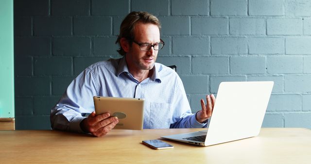 Businessman using laptop and tablet during video conference - Download Free Stock Images Pikwizard.com