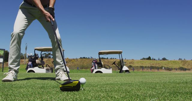 Golf Player Preparing to Swing with Golf Carts in Background on Sunny Day - Download Free Stock Images Pikwizard.com