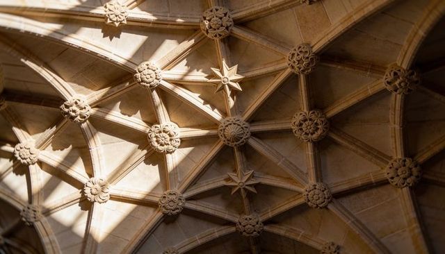 Gothic ribbed vault ceiling showcasing carved bosses and rosette details in sandstone cloister