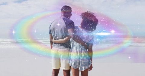 Couple embracing on beach with surreal rainbow glow