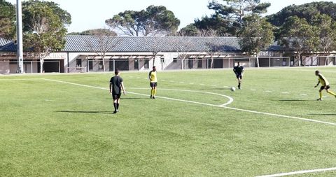 Soccer players practicing teamwork on sunny outdoor field