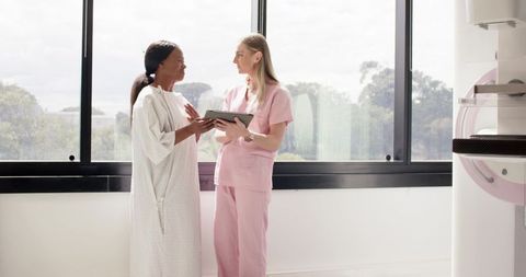 African American patient discussing mammogram with female technologist holding tablet