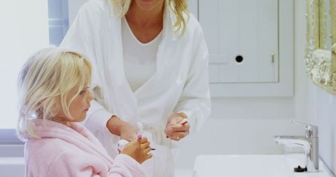 Mother Teaching Daughter Toothbrushing Routine in Bathroom