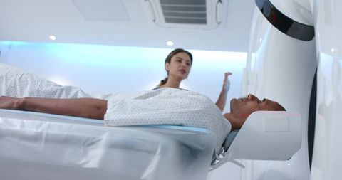 African american patient undergoing head mri while technologist operating advanced scanner