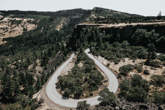 Perfect for travel blogs, adventure websites, tourism brochures, and nature documentaries. Highlights dramatic curves of a mountain road, lush forest surroundings, and stunning aerial perspective.
