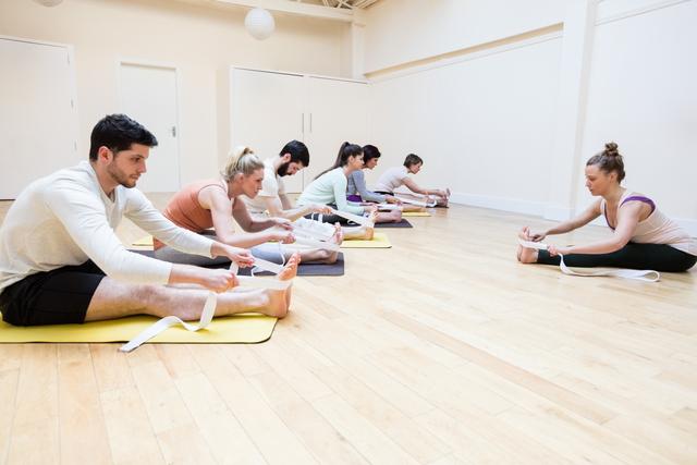 Trainer assisting group of people with stretching exercise - Download Free Stock Photos Pikwizard.com