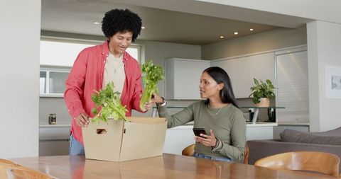 Couple Unpacking Groceries from Cardboard Box at Home Kitchen