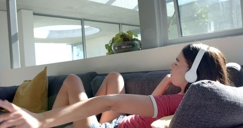 Teen Girl Relaxing on Couch Listening to Music with Headphones