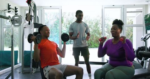 Diverse couple training with personal coach at home gym