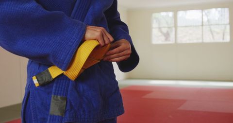 Judo Fighter Tying Yellow Belt in Martial Arts Gym