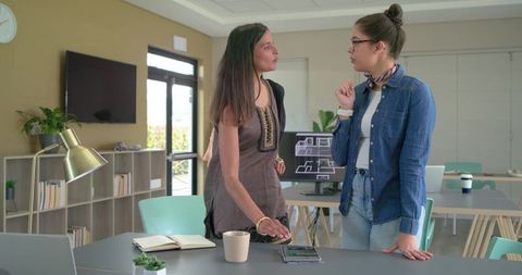 Diverse female design team reviewing architectural floor plans in modern coworking office