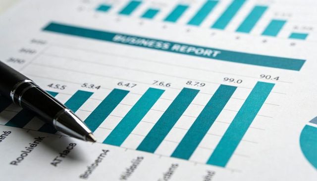 Closeup of teal bar chart showing financial growth with pen on business report analytics