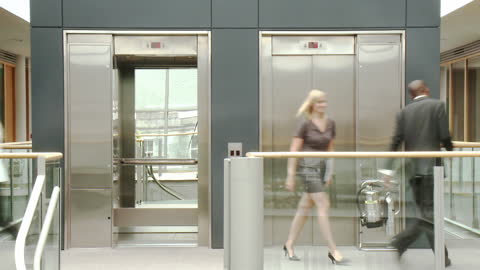 Business Professionals Emerging from Elevator in Modern Office
