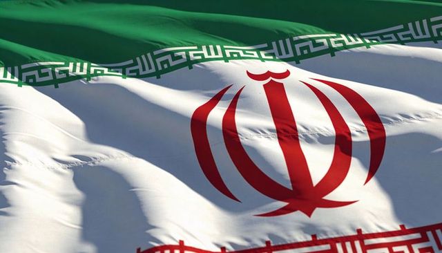 Sunlit waving iranian flag with red emblem and kufic border showing stitching and folds