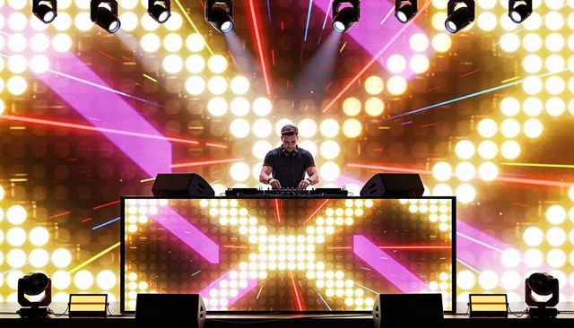 DJ Performing on Neon LED Stage With Vibrant Light Show and Mixer