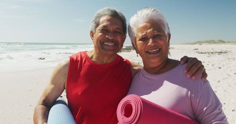 Hispanic Senior Couple Smiling on Beach with Yoga Mats