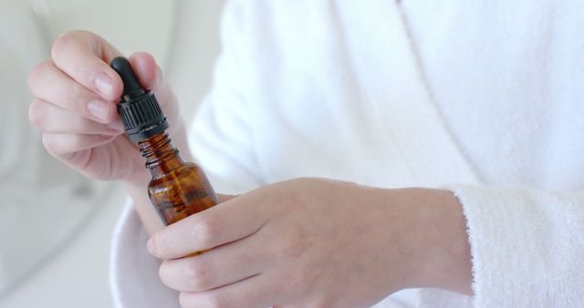 Close-Up of Hands Holding Amber Dropper Bottle for Skincare - Download Free Stock Images Pikwizard.com