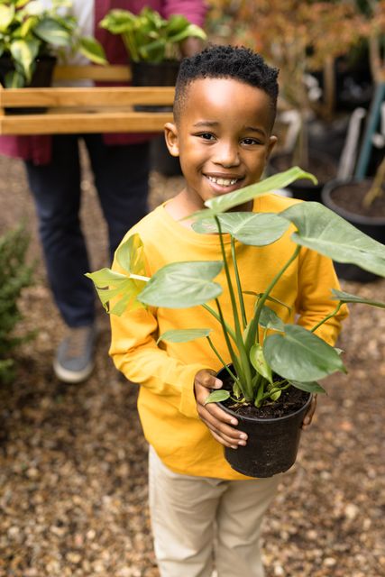 Portrait of happy senior african american man with his grandson in garden. Spending quality time in garden nursery concept.