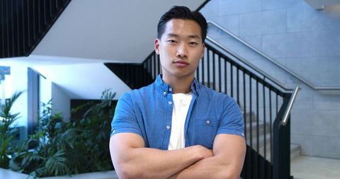 Confident young professional standing with arms crossed in modern stairwell