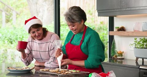 Mother and Daughter Decorating Christmas Cookies in Festive Kitchen