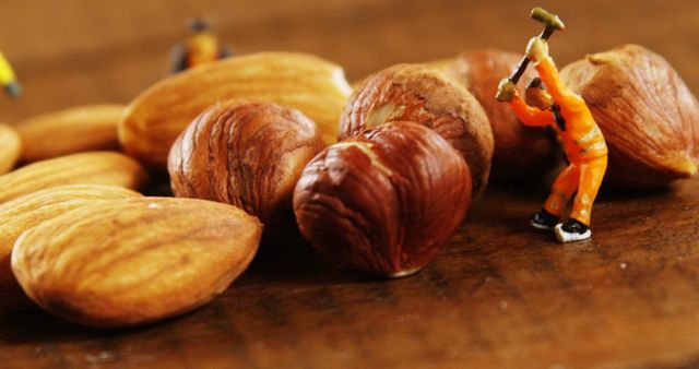 Close up of nuts, almonds and worker figurine on brown counter top. Organic food, healthy lifestyle, work and professional.