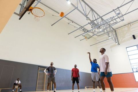 Men shooting free throw while teammates watch and prepare for rebound in indoor gym