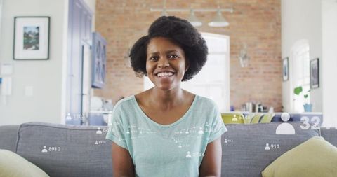 Smiling woman livestreaming from modern living room with social media overlay icons