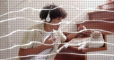 Curly-haired man wearing headphones petting cat in open drawer with halftone dot overlay