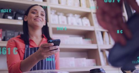Smiling barista showing mobile payment at boutique cafe counter with takeaway cup