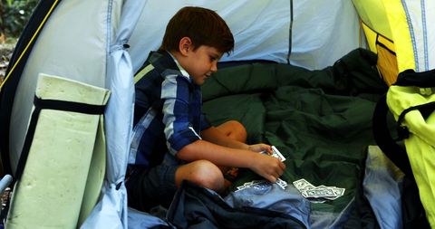 Young Boy Playing Cards Inside Tent at Campsite
