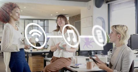 Creative team of women collaborating in modern office with digital icons overlay