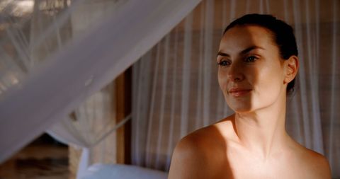 Serene Woman Relaxes in Sunlit Room with Reflective Gaze - Download Free Stock Images Pikwizard.com
