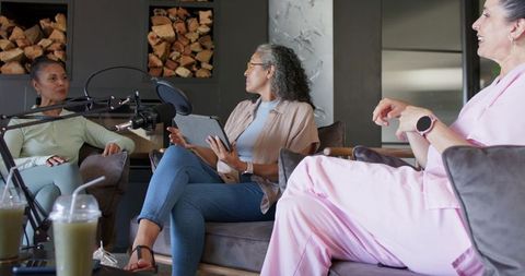 Women recording podcast in cozy lounge discussing health and wellness with microphone
