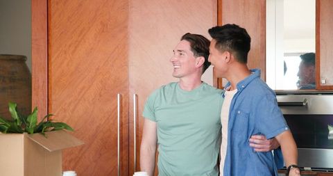 Happy lgbtq+ couple unpacking in modern kitchen