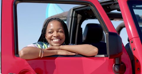 Happy Young Woman Enjoying Leisurely Road Trip in Red Convertible