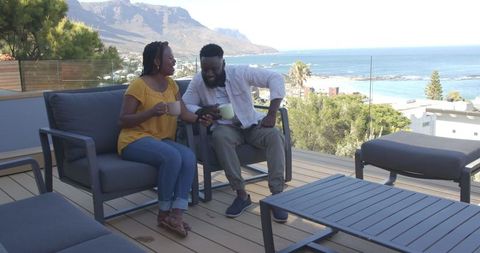 Couple Drinking Coffee on Ocean View Balcony Sharing Smartphone