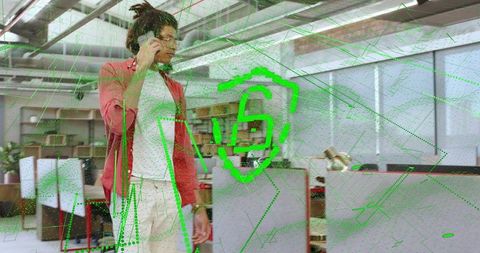 Young man walking talking on smartphone in modern office with green AR security shield