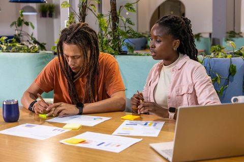 African American Coworkers Brainstorming at Coworking Table with Laptop and Sticky Notes